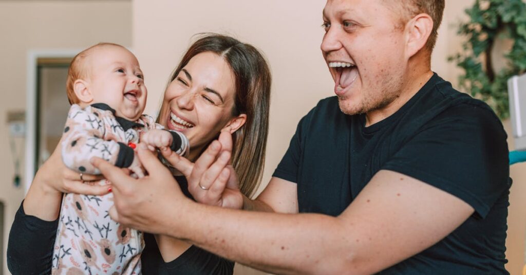 A happy family of three laughing and bonding indoors, showcasing love and warmth.